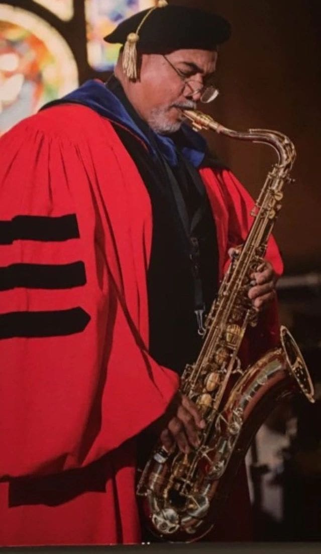 A man in red robe holding a saxophone.