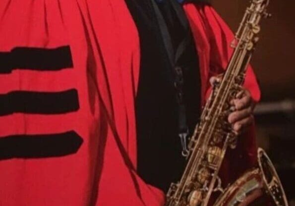 A man in red robe holding a saxophone.